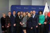 Grupa osób w formalnych strojach pozuje do zdjęcia na tle ścianki Ministerstwa Funduszy i Polityki Regionalnej.