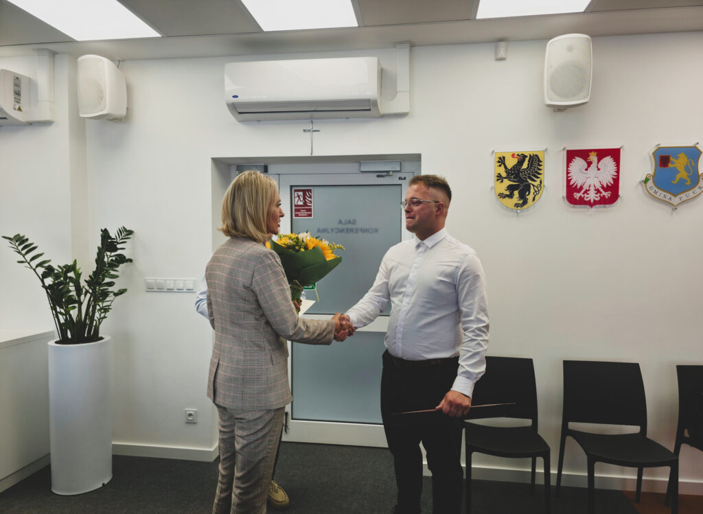 Sekretarz wręcza kwiaty sołtysowi i składa gratulacje