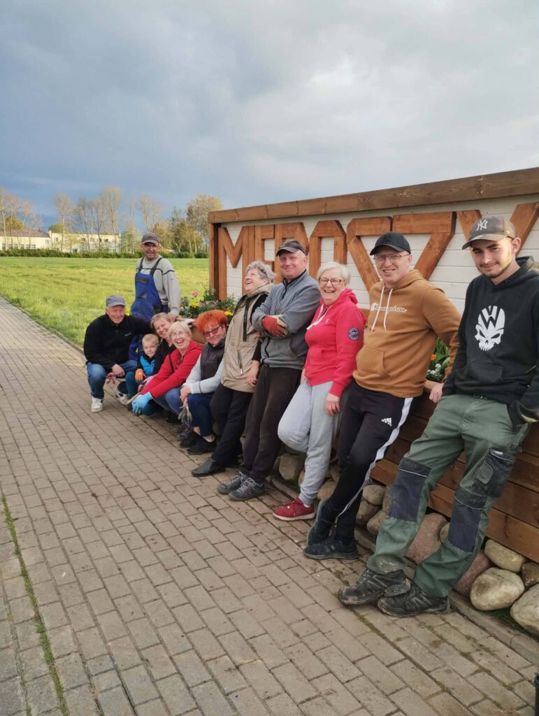 Mieszkańcy Mieroszyna przy nowych nasadzeniach i napisie Mieroszyno