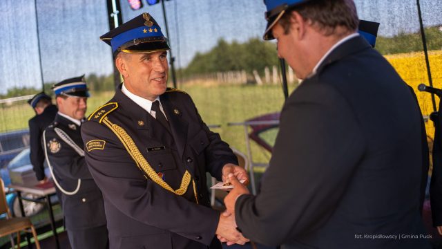 Asp. sztab. Zaczek Maciej i mężczyzna w garniturze ściskają dłonie na scenie