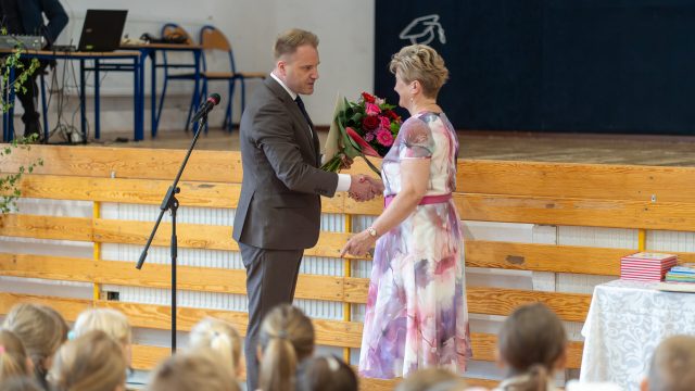 Wójt wręcza kwiaty odchodzącej na emeryturę dyrektor szkoły