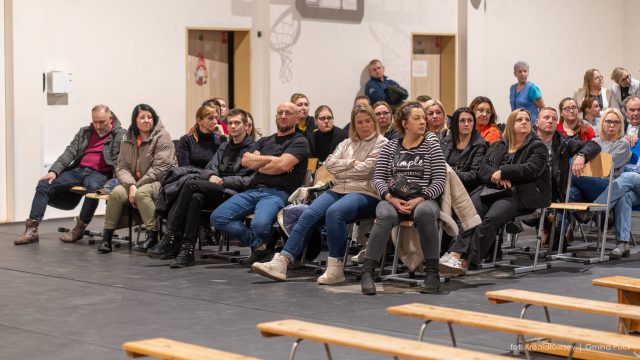 Mieszkańcy gminy Puck siedzący na krzesłach w sali gimnastycznej.