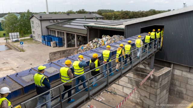 Radni przechodzą kładką technologiczną nad linią sortującą odpady komunalne